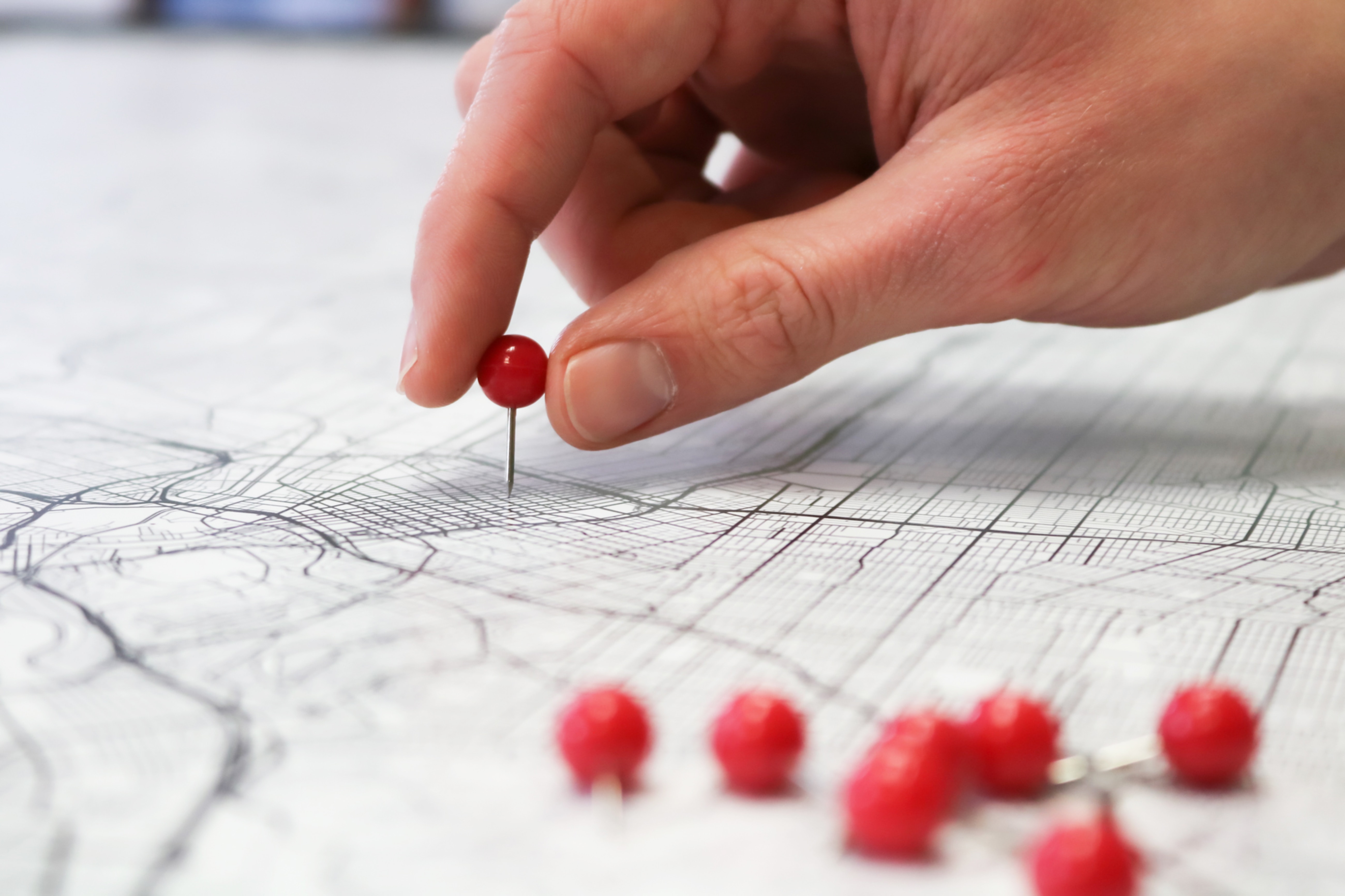 Image of person using a pin to mark a location on a map